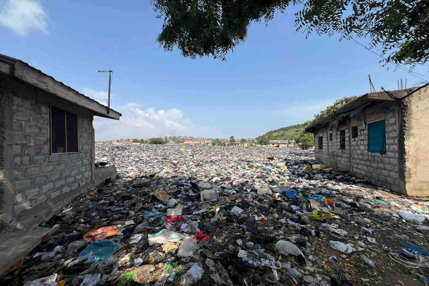 Textiles and other plastic waste outside houses at the Weija Ashbread landfill, an older textile dump site upriver from the Densu Delta protected wetlands, outside Accra, Ghana.